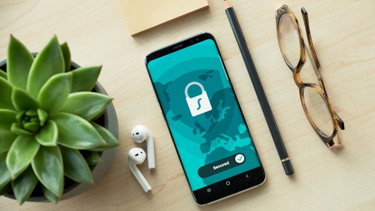 Secured online - a table with a phone, glasses, earphones and a plant